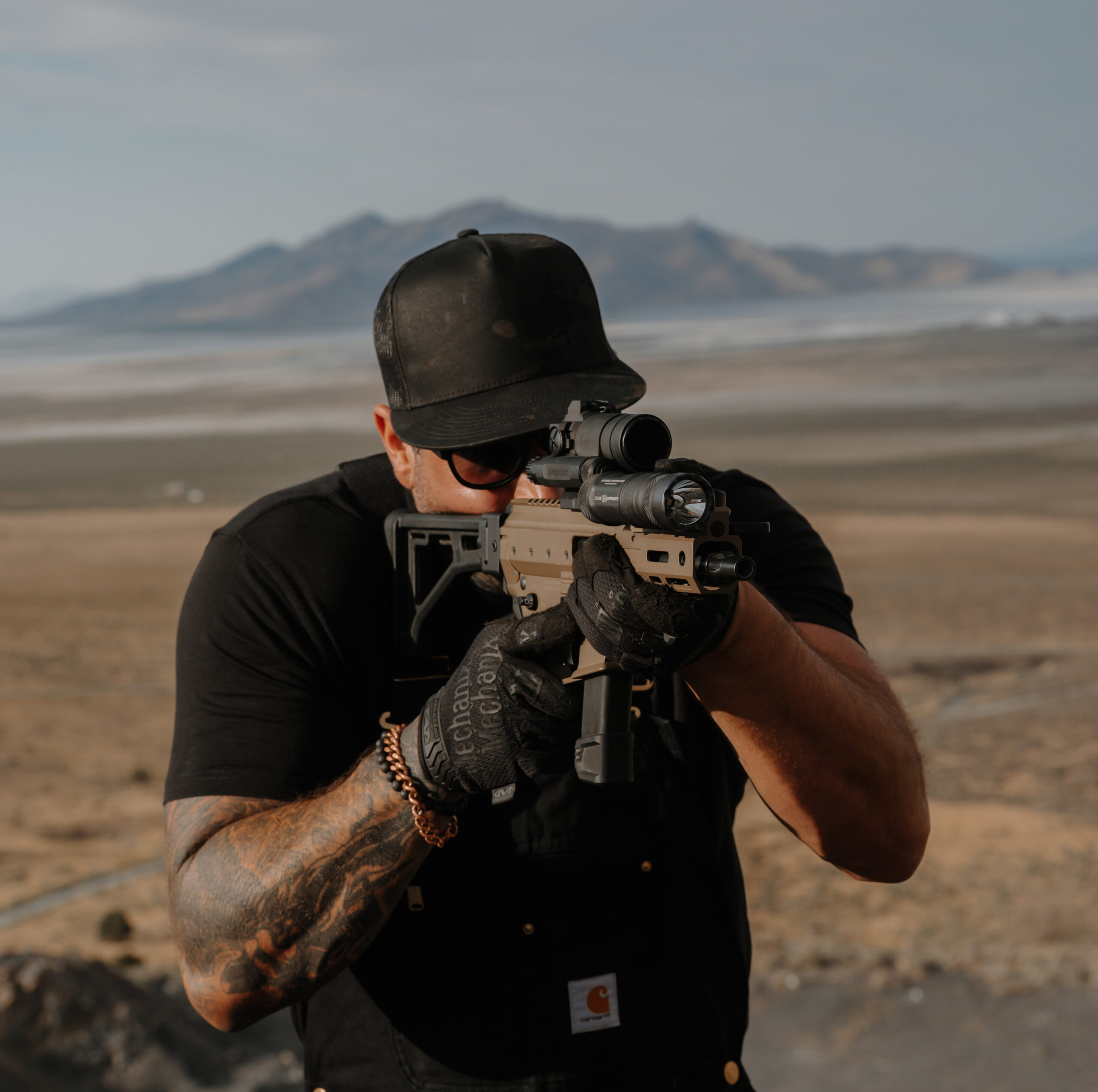 Man aiming Angstadt Arms MDP-9 in a location with desert mountain scenery